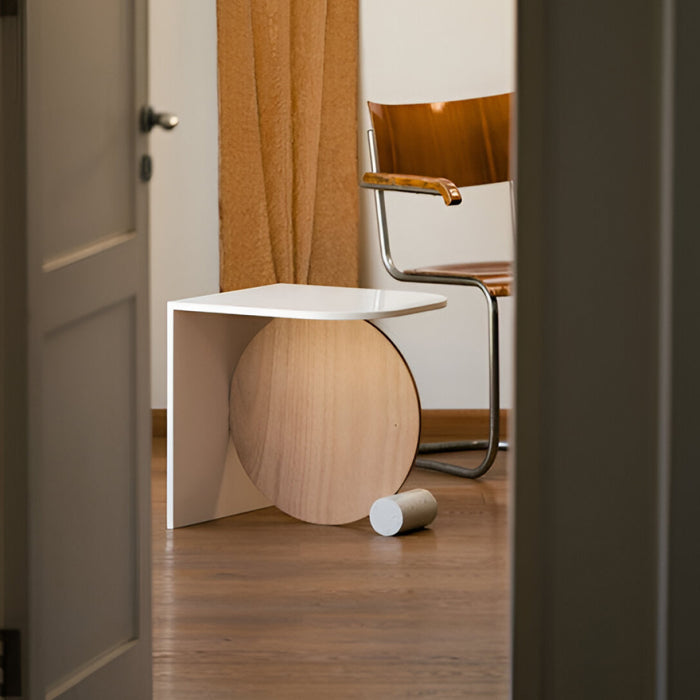 Modern side table with wooden base and white top in a room setting.