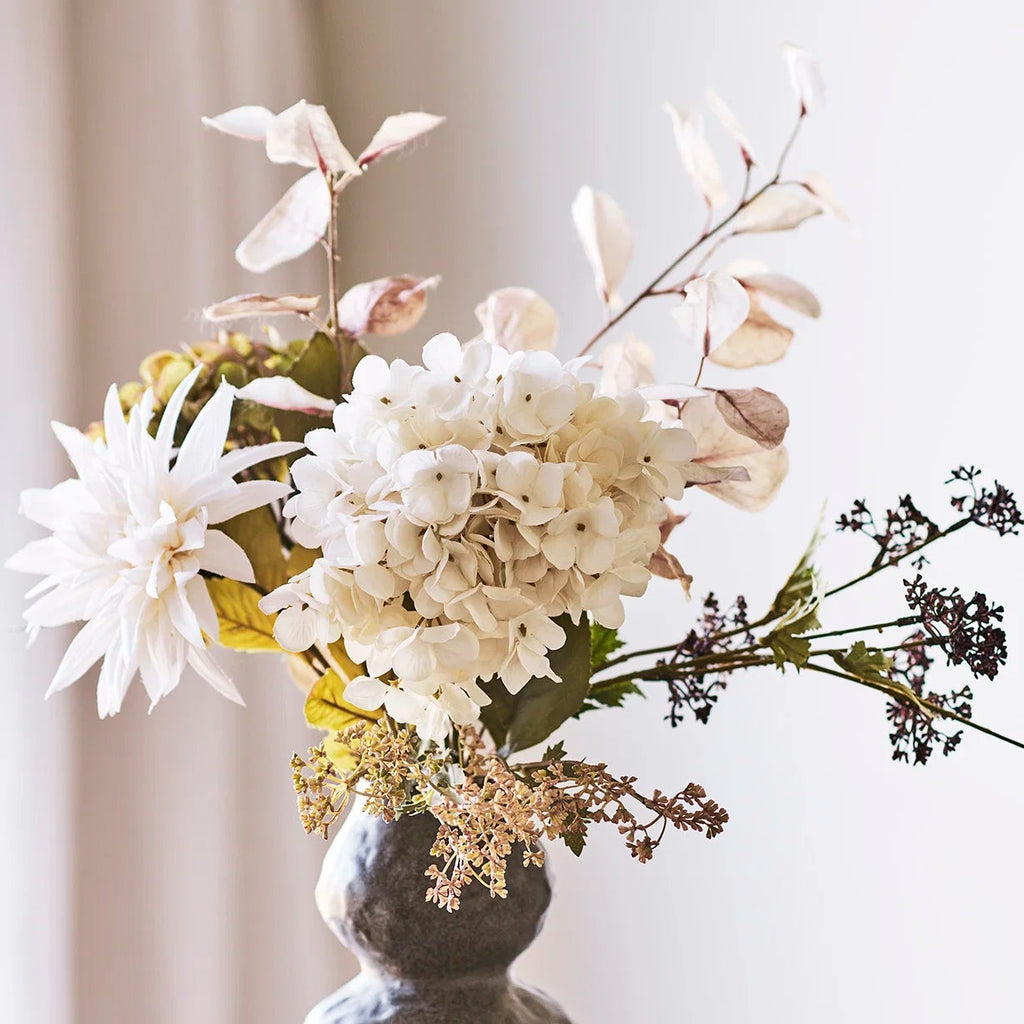 Decorative vase with a bouquet of flowers on a light surface.