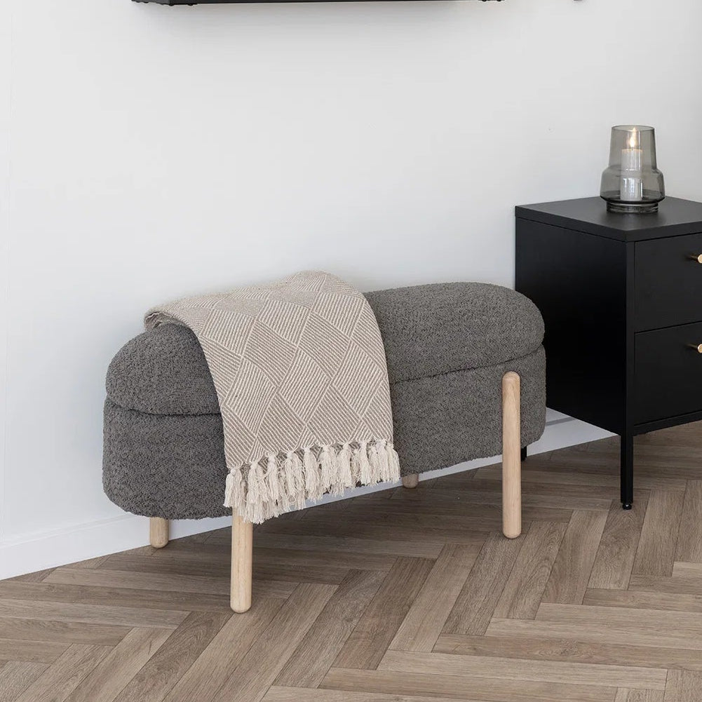 Modern interior with black wall cabinet, gray ottoman, and plant on a white wall.