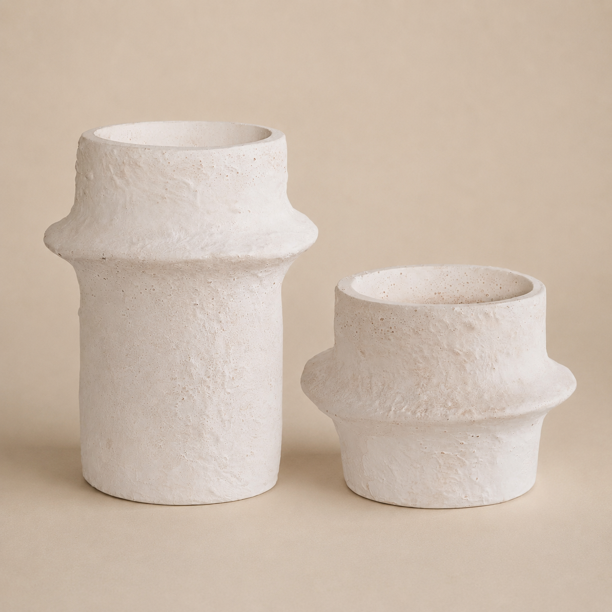 Two white textured vases on a beige background