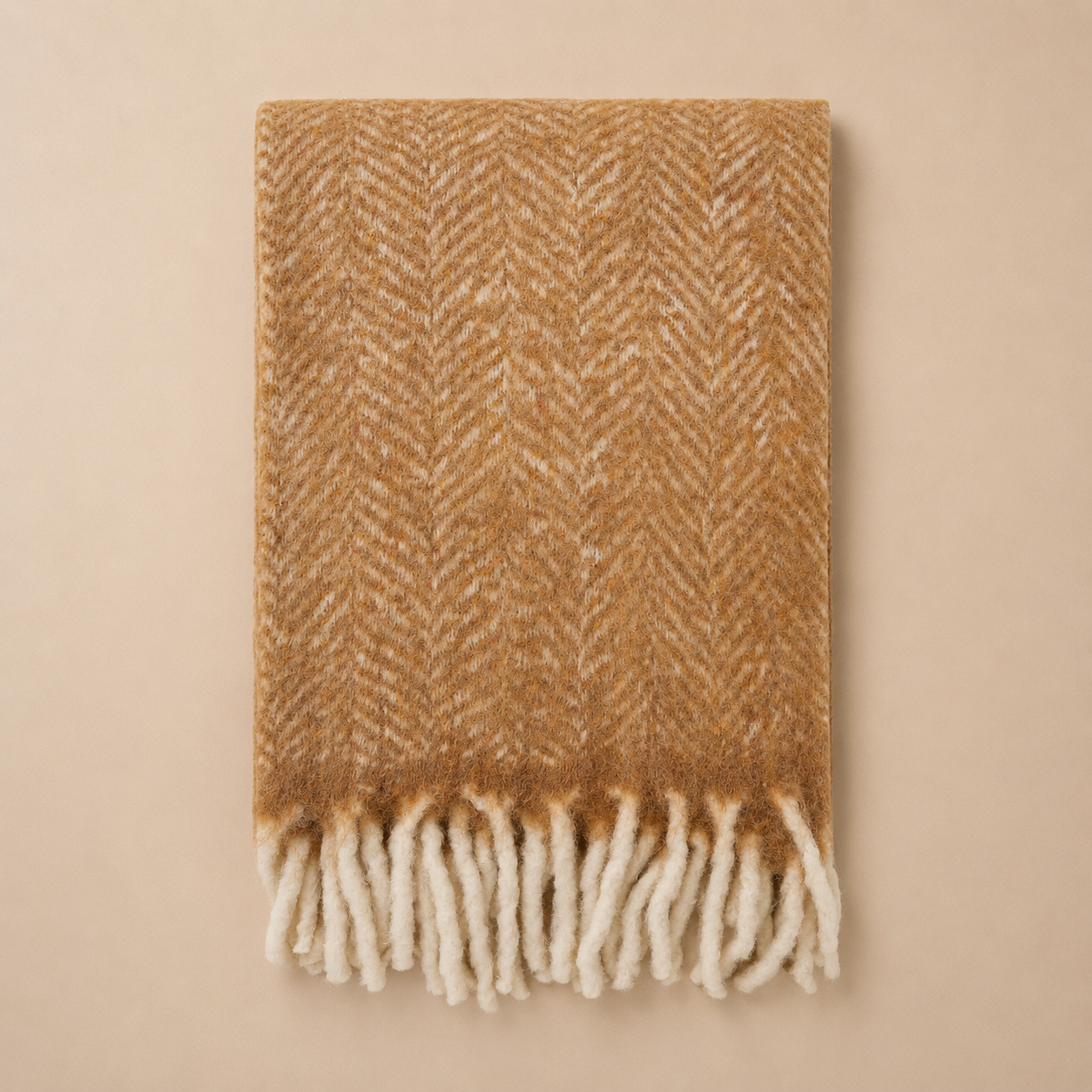 Brown and beige herringbone patterned throw blanket with white fringe on a beige background