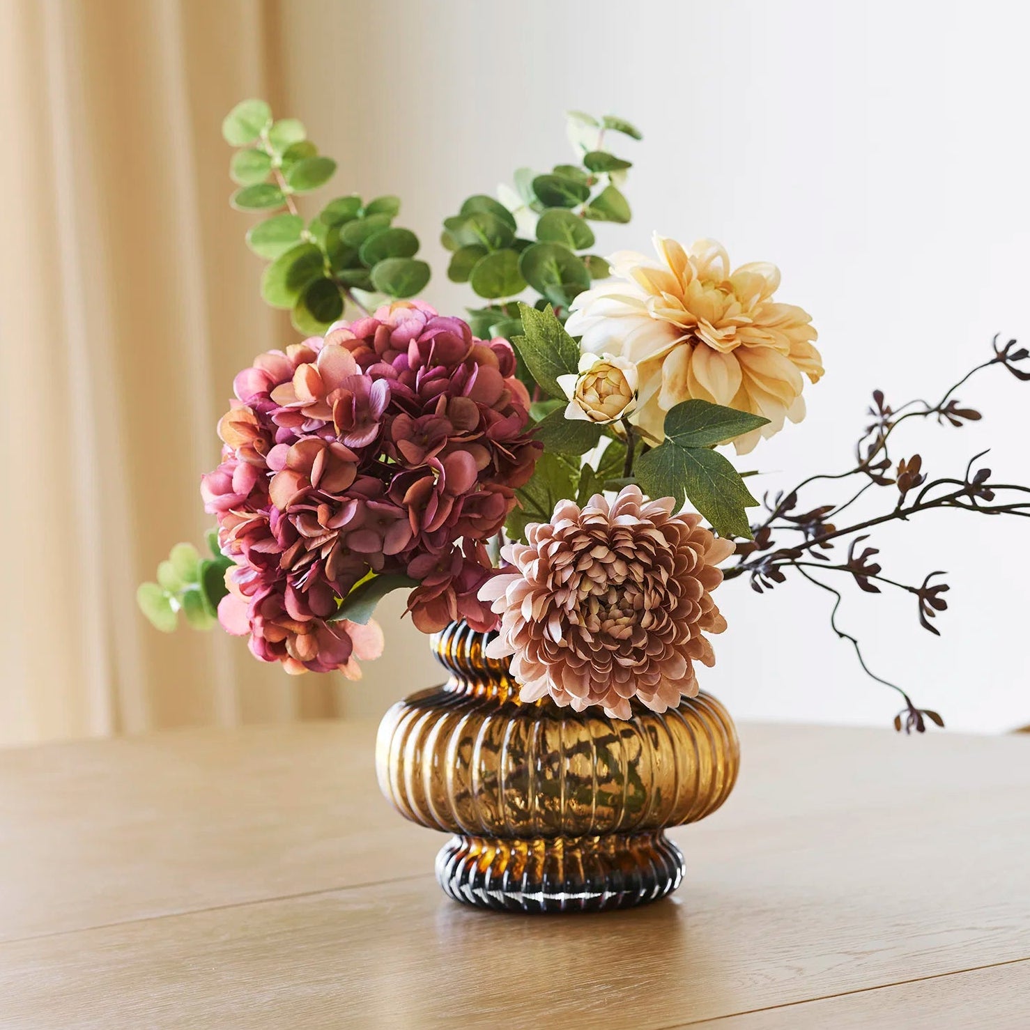 Decorative vase with flowers on a wooden surface