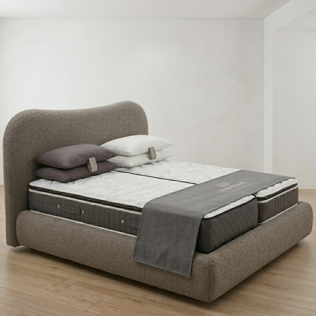 Bed with mattress and pillows on a wooden floor in a minimalistic room.