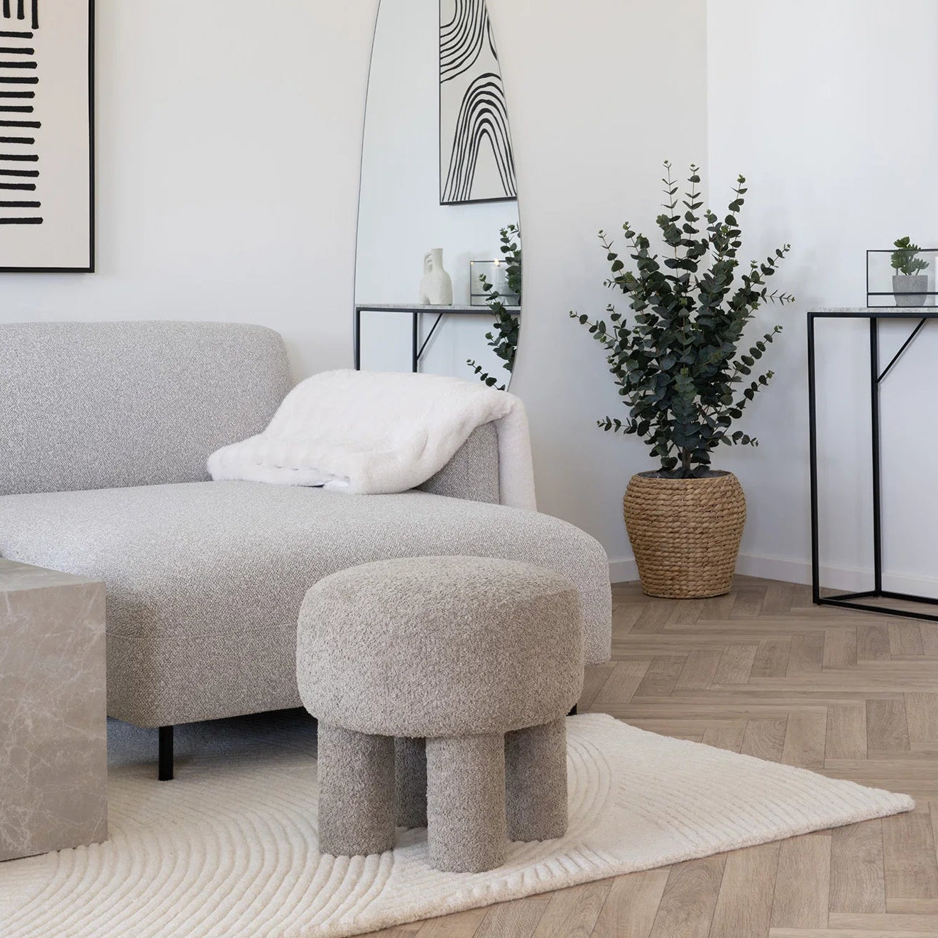 Modern living room with a gray sofa, ottoman, and decorative elements.
