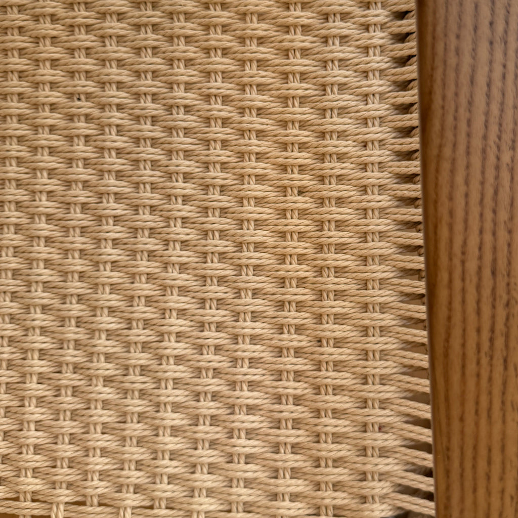 Close-up of a wicker chair with wooden armrests.