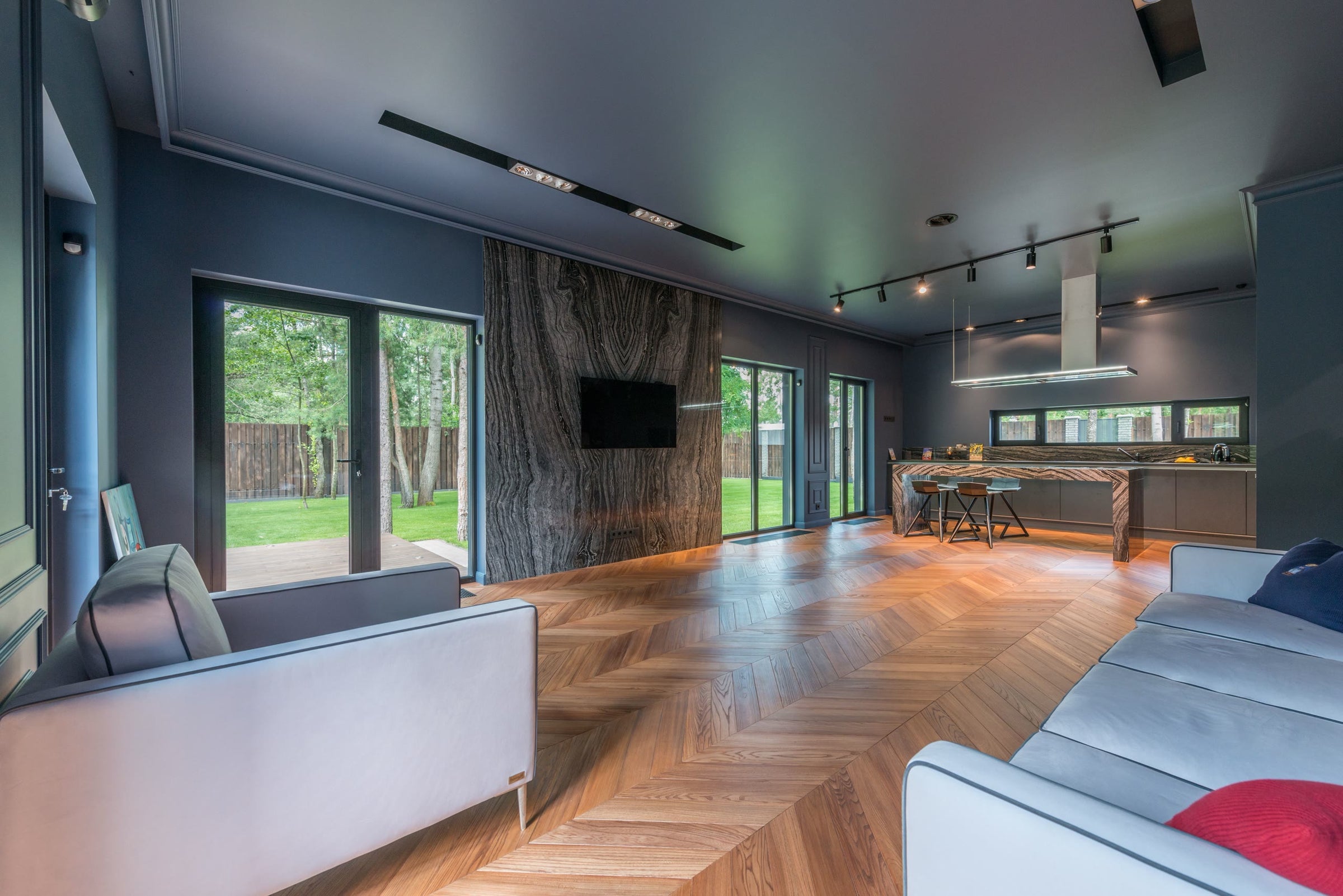 A dark contemporary living space with herringbone parquet and full-height glazing
