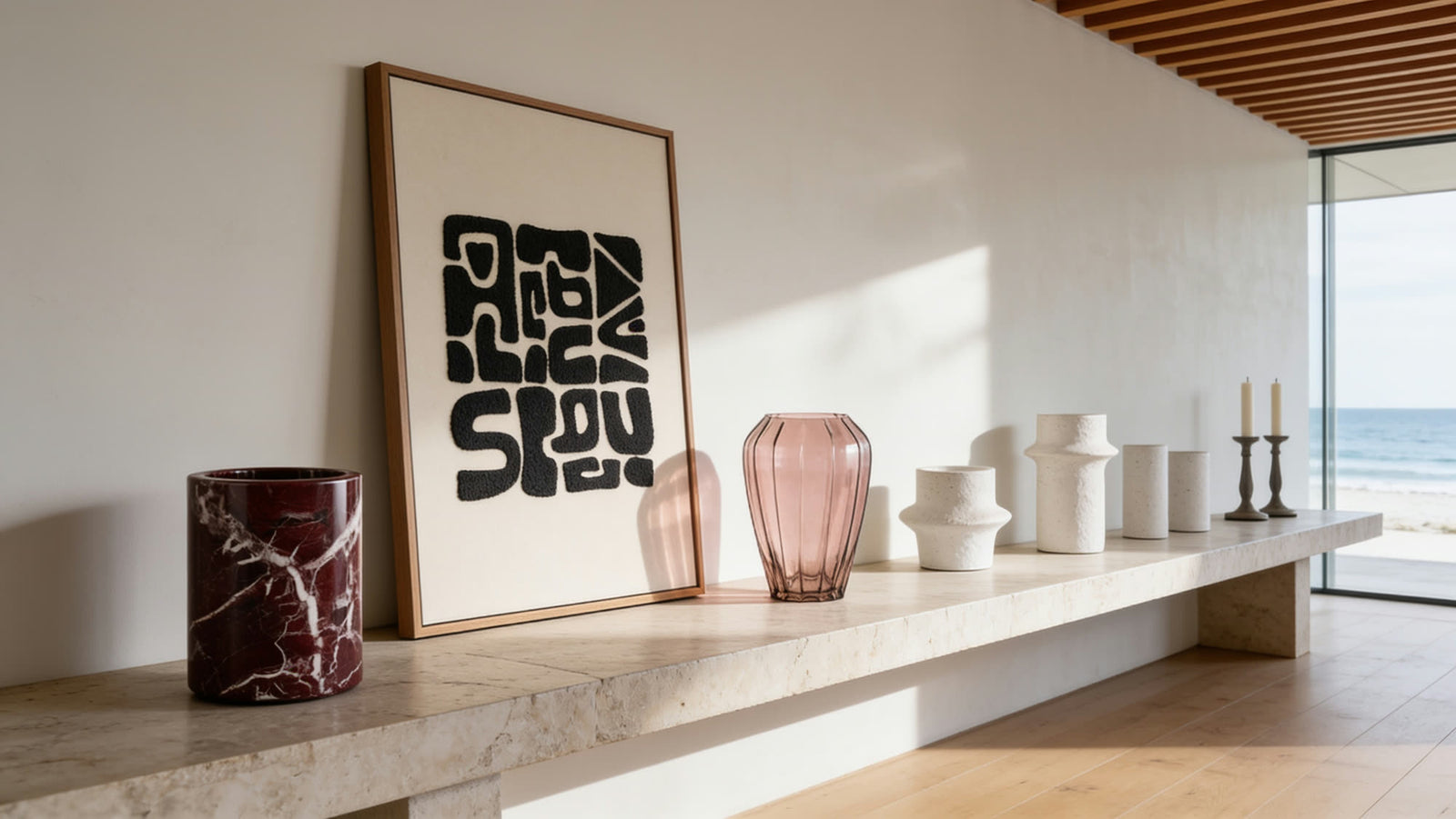 Ceramic vases, a glass vase and candle holders arranged on a travertine console