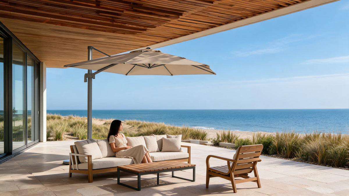 A stone terrace with an outdoor sofa and cantilever parasol above the beach