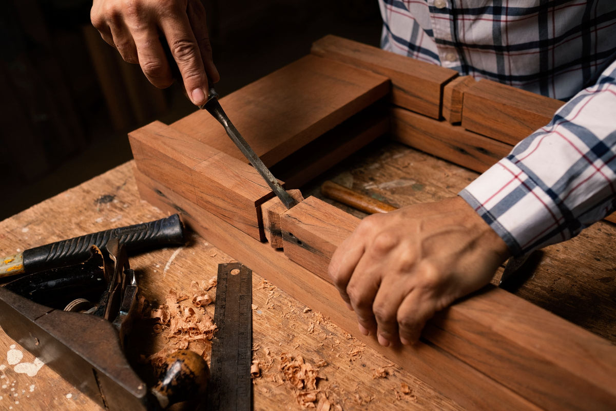 Hands cutting a joint by hand in a timber frame