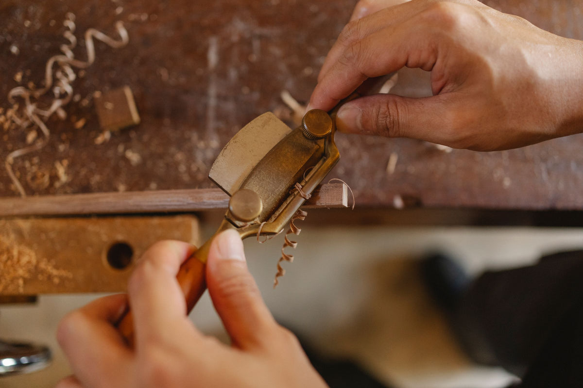 A craftsman working a moulding with a router plane at the bench