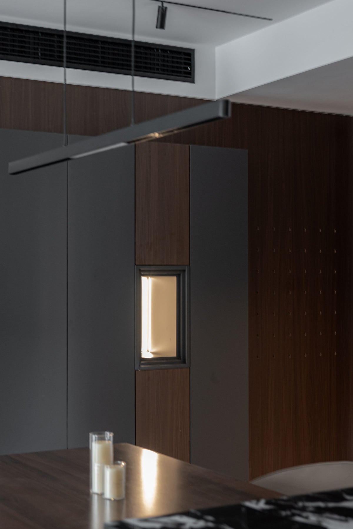 Dark timber cabinetry lit by a narrow band of warm light