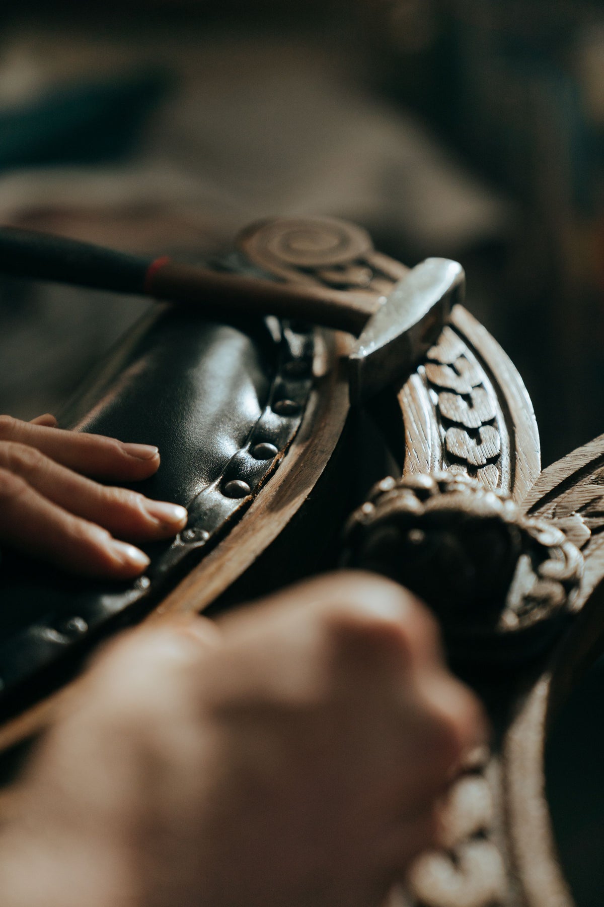 Hands resting on dark leather beside a carved timber detail