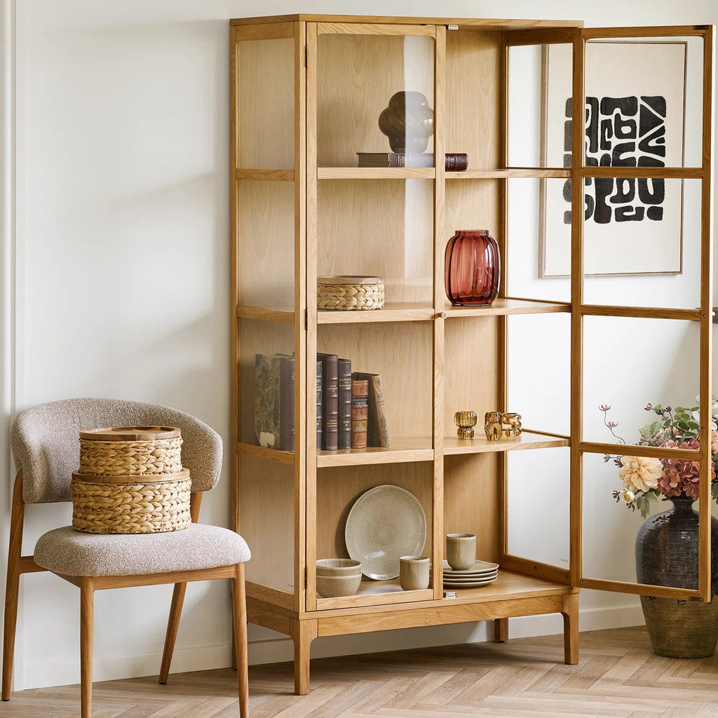 Wooden bookshelf with decorative items in a room with a chair and rug.