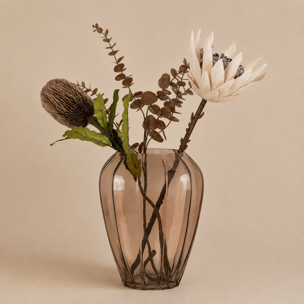 Glass vase with dried flowers on a beige background