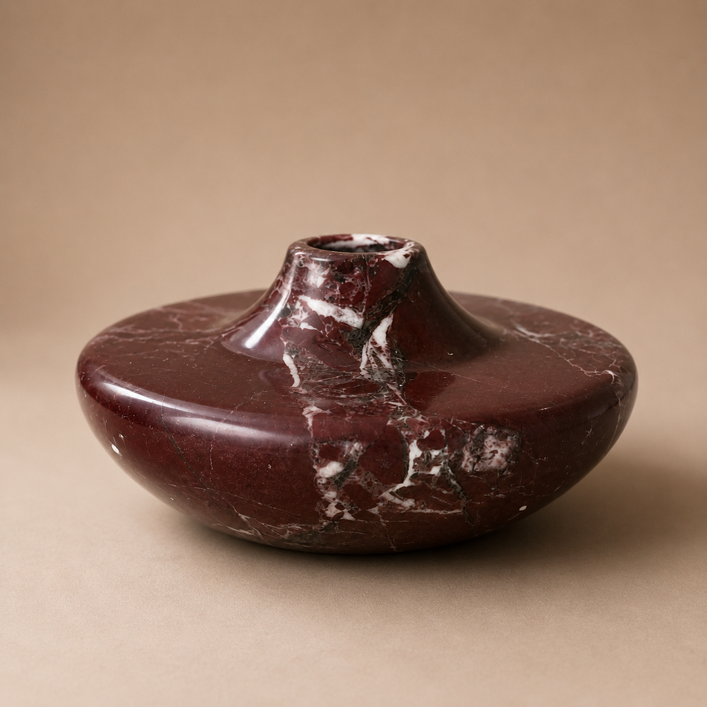 Maroon ceramic vase with a textured surface on a beige background
