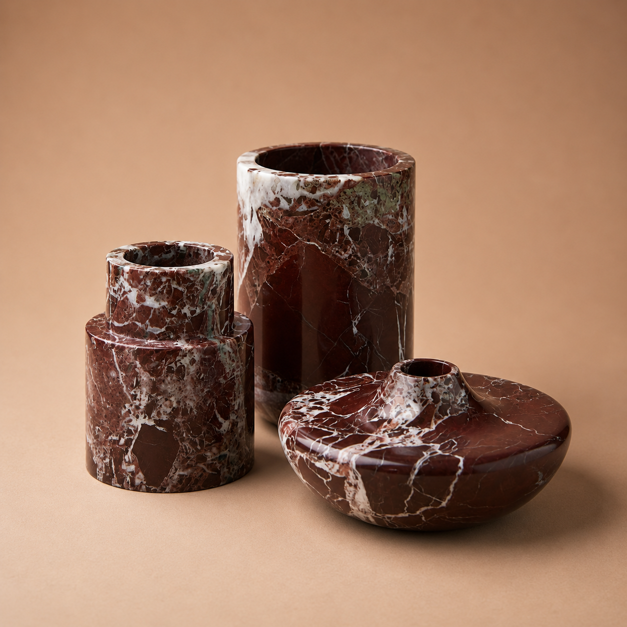 Set of three brown marble vases on a beige background